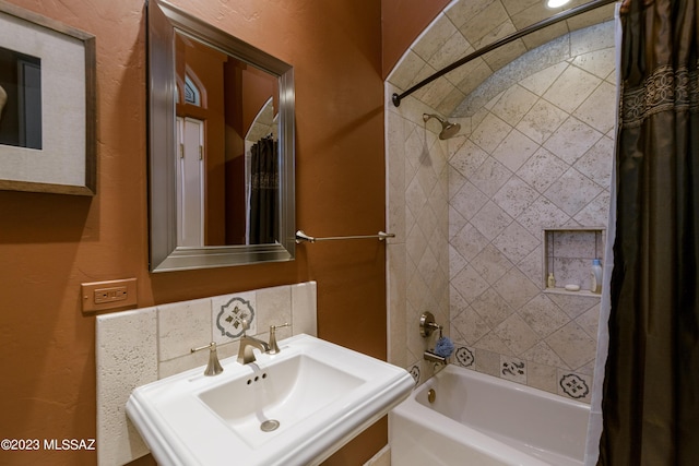 bathroom with backsplash, shower / bathtub combination with curtain, and sink