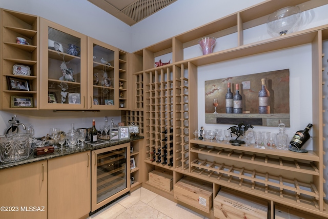 wine cellar featuring bar, light tile patterned floors, and beverage cooler