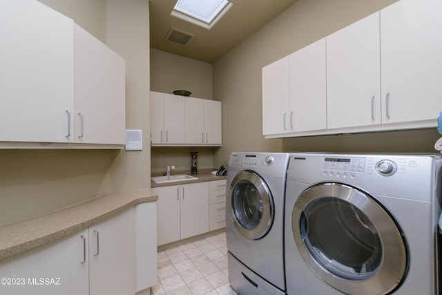 laundry room featuring cabinets, washing machine and dryer, a skylight, and sink