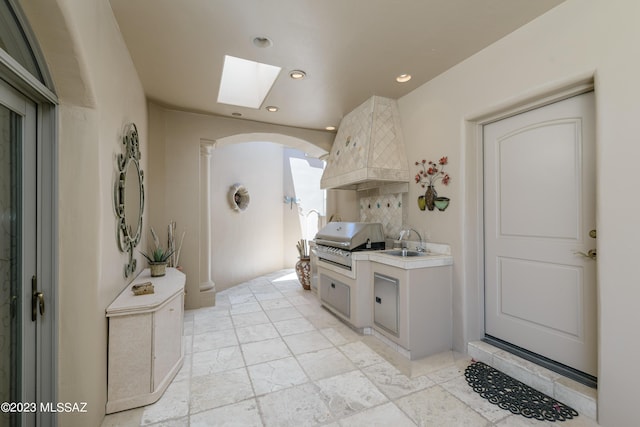 bathroom with a skylight, decorative backsplash, and sink