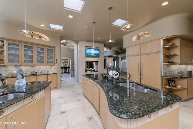 kitchen featuring a skylight, sink, pendant lighting, and a large island with sink