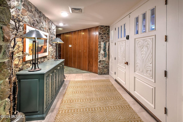 corridor featuring wooden walls and light tile patterned floors