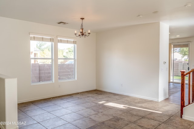 tiled empty room featuring an inviting chandelier