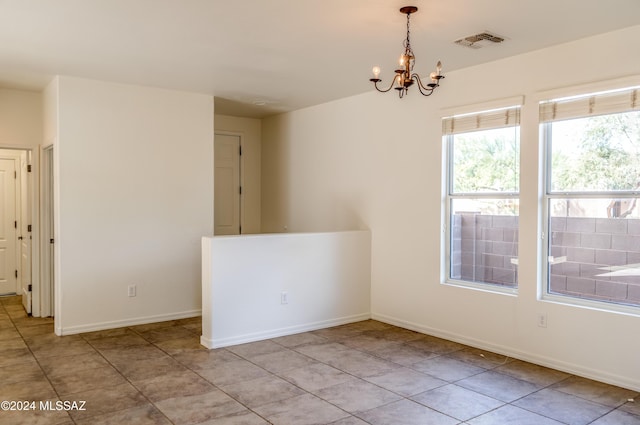 spare room featuring a notable chandelier and light tile patterned floors