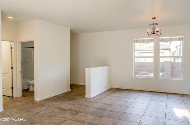 tiled empty room featuring an inviting chandelier