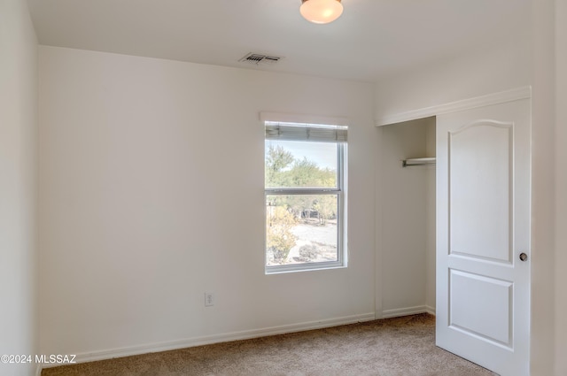 unfurnished bedroom featuring light colored carpet and a closet