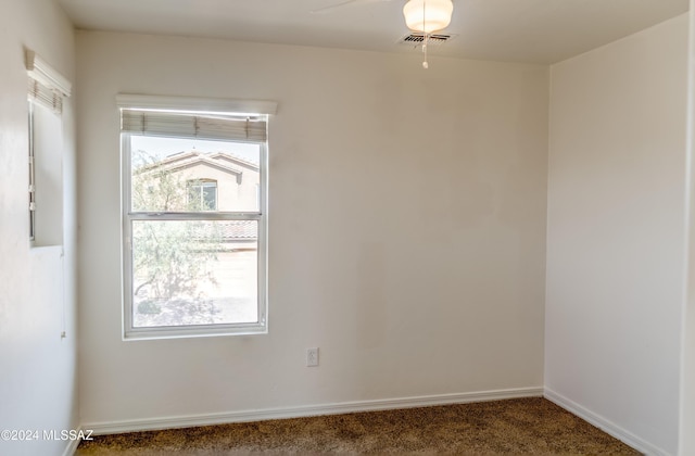 unfurnished room with a wealth of natural light and dark carpet