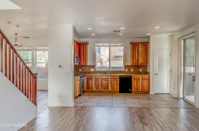 kitchen featuring sink, stainless steel appliances, tasteful backsplash, a notable chandelier, and light hardwood / wood-style floors