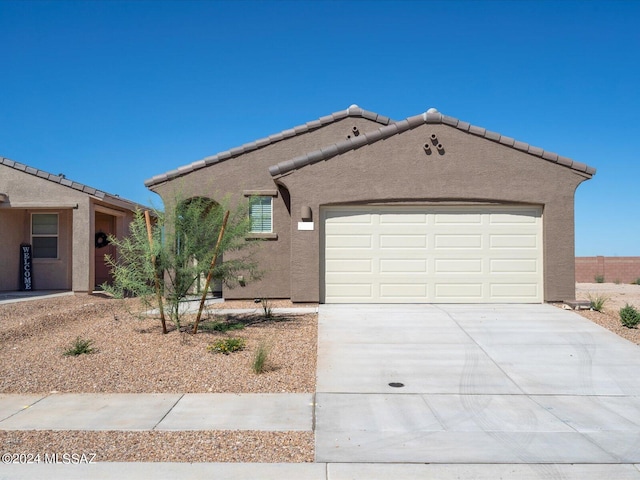 mediterranean / spanish-style house with a tile roof, a garage, driveway, and stucco siding