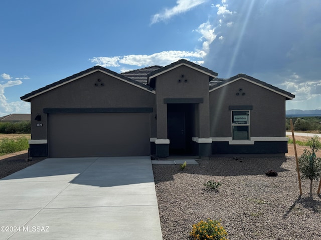 ranch-style home featuring stucco siding, a garage, concrete driveway, and a tiled roof