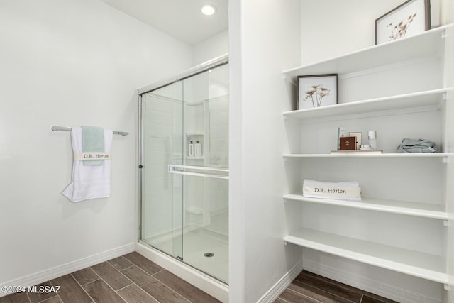 full bath with a shower stall, baseboards, and wood finish floors