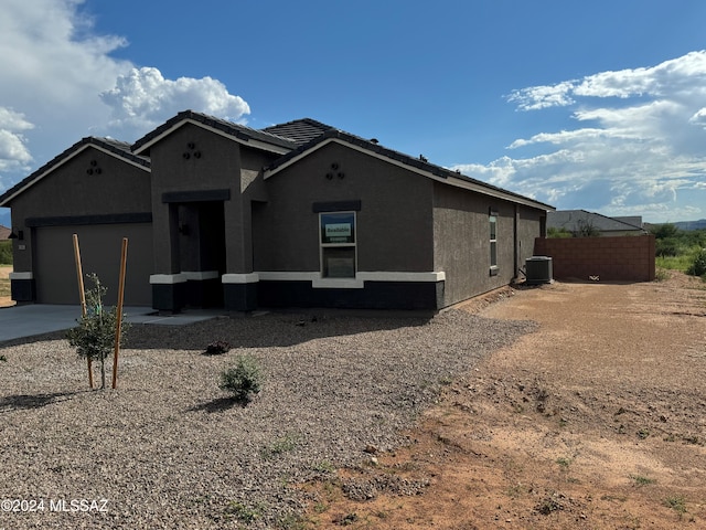 view of front of property with stucco siding, driveway, fence, cooling unit, and a garage