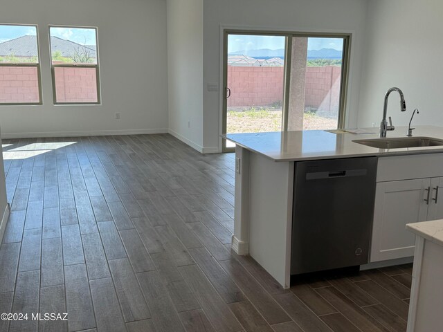 kitchen featuring wood finish floors, dishwasher, light countertops, white cabinetry, and a sink