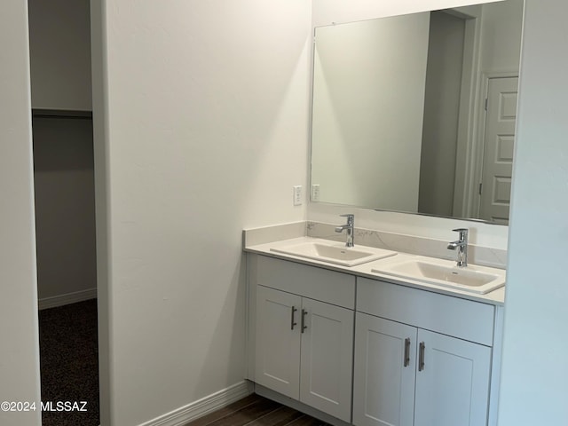 full bathroom featuring double vanity, wood finished floors, baseboards, and a sink