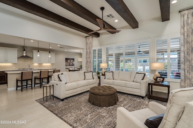 living room featuring beam ceiling, ceiling fan, sink, and light hardwood / wood-style floors