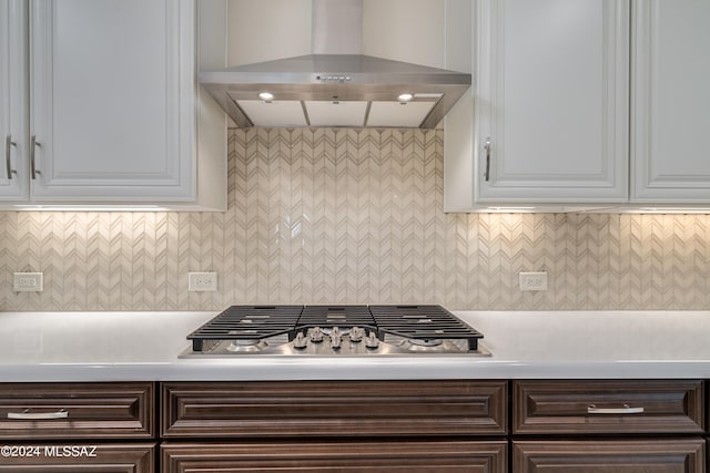 kitchen with white cabinets, dark brown cabinets, stainless steel gas cooktop, and wall chimney exhaust hood