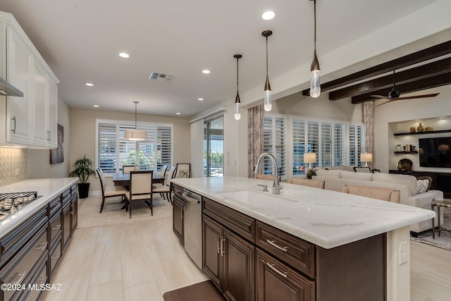 kitchen with appliances with stainless steel finishes, a kitchen island with sink, ceiling fan, sink, and white cabinets