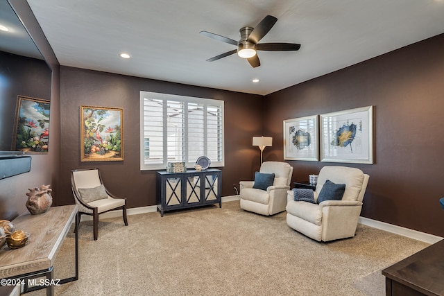 living area featuring light colored carpet and ceiling fan