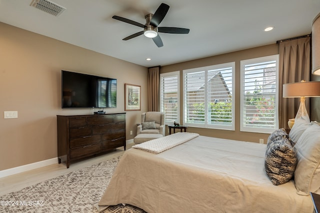 bedroom with ceiling fan, light hardwood / wood-style floors, and multiple windows