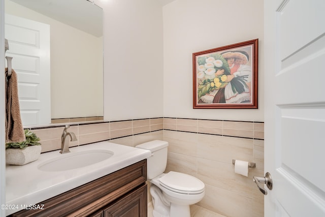 bathroom with vanity, toilet, and tile walls