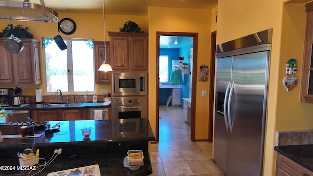 kitchen featuring built in appliances, a wealth of natural light, sink, and light tile patterned floors