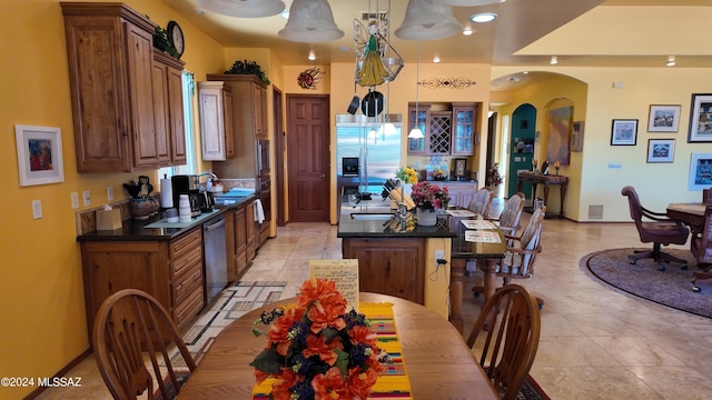 kitchen featuring a center island, a kitchen breakfast bar, light tile patterned floors, decorative light fixtures, and stainless steel appliances