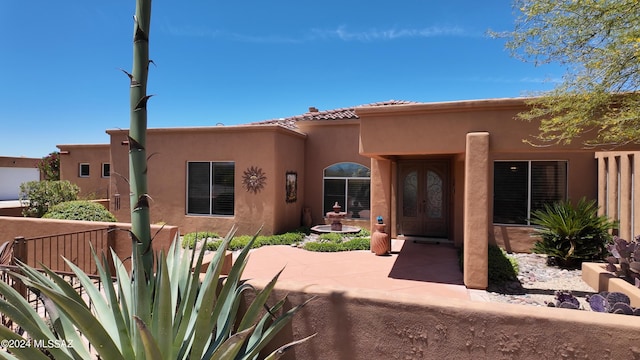 pueblo revival-style home featuring french doors and a patio area