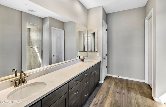 bathroom featuring hardwood / wood-style flooring, a tile shower, and vanity