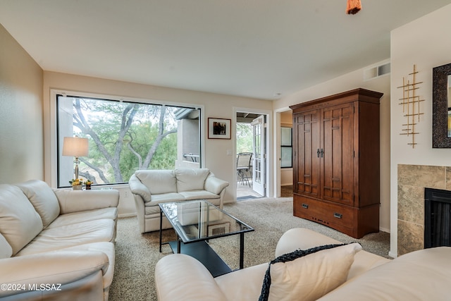 carpeted living room featuring a tiled fireplace