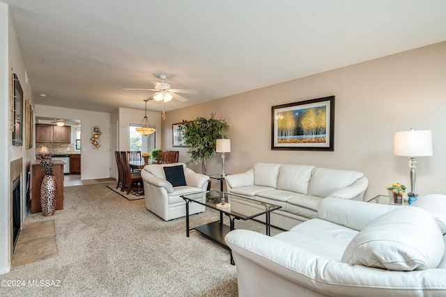 living room featuring a ceiling fan, light colored carpet, and a fireplace