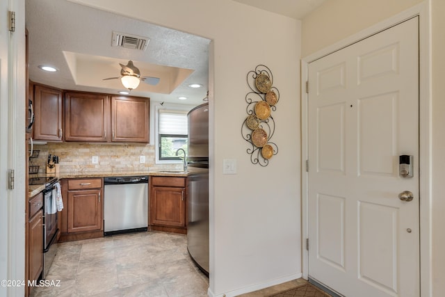 kitchen with a tray ceiling, brown cabinets, visible vents, appliances with stainless steel finishes, and a sink