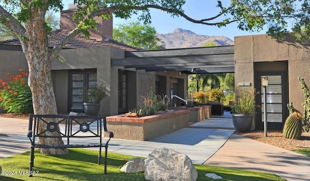 view of front facade featuring a mountain view, a chimney, and stucco siding