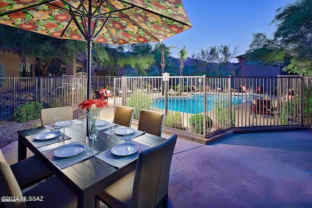 view of patio with outdoor dining area, fence, and a community pool