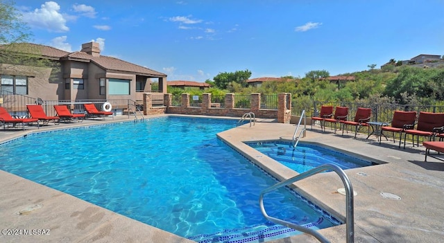 community pool with a patio area, fence, and a community hot tub