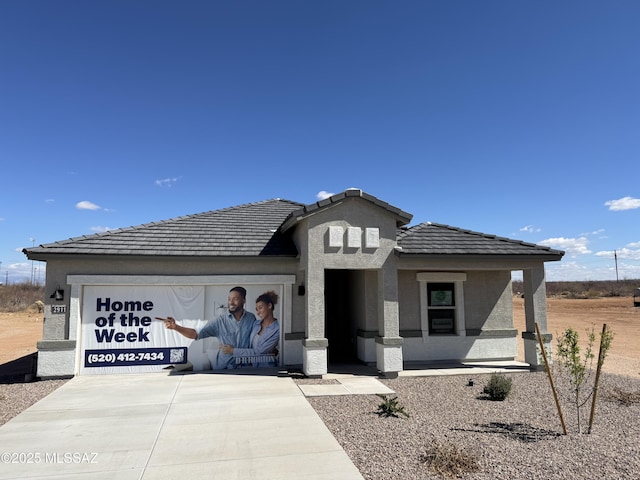 view of front facade featuring a garage, driveway, a tile roof, and stucco siding