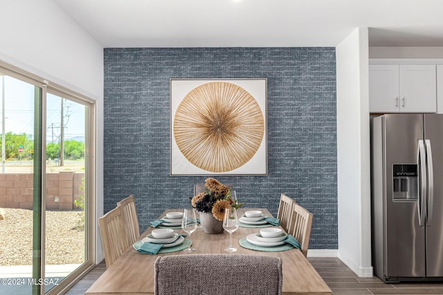 dining room featuring an accent wall, baseboards, and wood finished floors