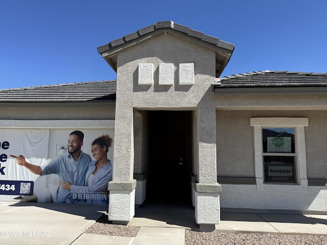 entrance to property with a tiled roof and stucco siding