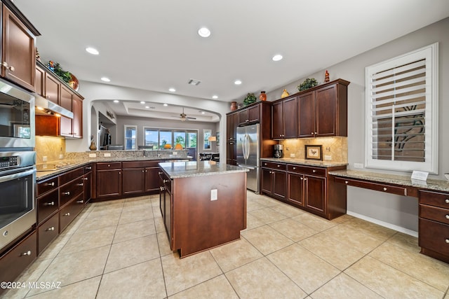 kitchen featuring a center island, backsplash, ceiling fan, kitchen peninsula, and stainless steel appliances