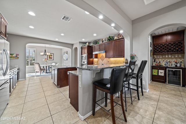 kitchen featuring a center island, beverage cooler, tasteful backsplash, dark stone counters, and pendant lighting