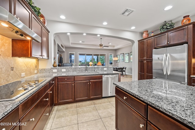 kitchen featuring a raised ceiling, sink, ceiling fan, appliances with stainless steel finishes, and kitchen peninsula