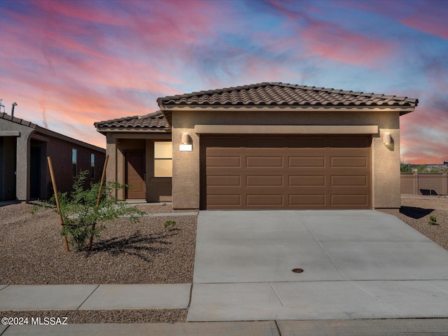 view of front of house with a tile roof, concrete driveway, stucco siding, and an attached garage