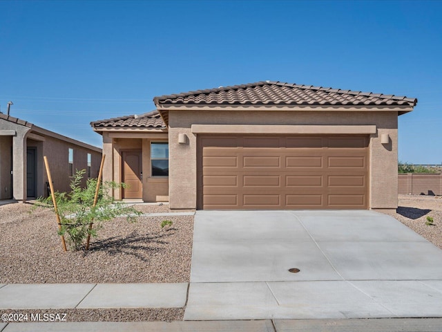 view of front facade featuring a tiled roof, driveway, stucco siding, and an attached garage