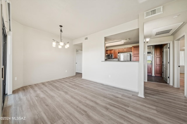 unfurnished living room featuring light wood-type flooring and a chandelier