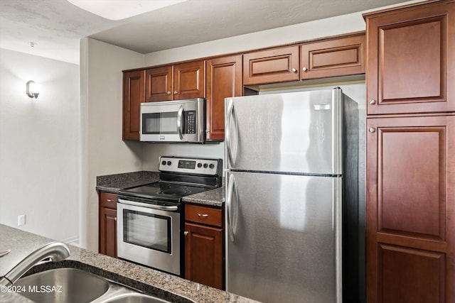 kitchen with sink, appliances with stainless steel finishes, and dark stone counters