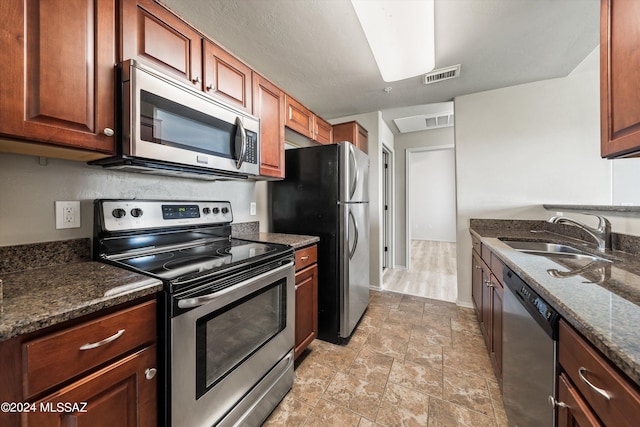 kitchen with sink, stainless steel appliances, and dark stone counters