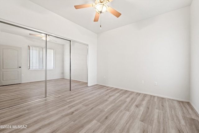 unfurnished bedroom featuring ceiling fan, a closet, and light wood-type flooring