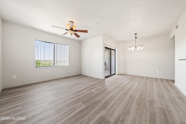 empty room featuring ceiling fan with notable chandelier and light hardwood / wood-style floors