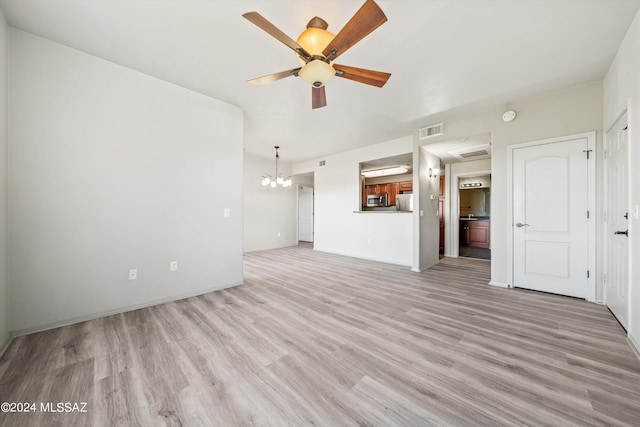 unfurnished living room with ceiling fan with notable chandelier and light hardwood / wood-style flooring