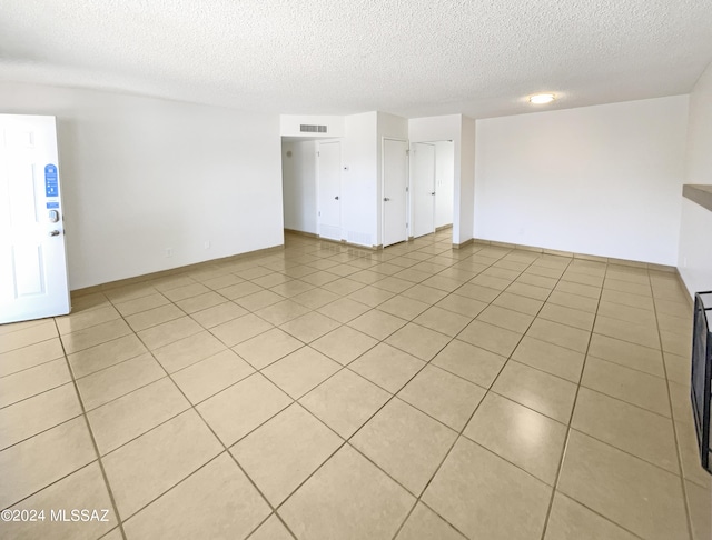 tiled empty room with a textured ceiling