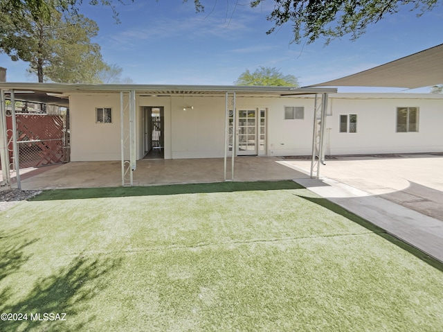 rear view of house featuring a lawn and a patio